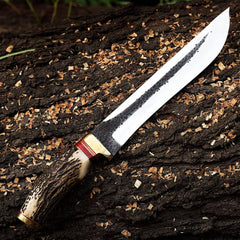 Custom forged Bowie knife with mirror-polished 1095 high carbon steel blade, natural hammer marks, stag antler handle, and cowhide leather sheath.