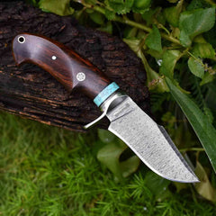 A close-up of a 10-inch Damascus hunting knife with a ladder pattern blade, stainless steel hilt, and walnut wood handle.