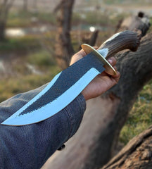Sharp clip point blade of a hand-forged Bowie knife with brass finger guard.
