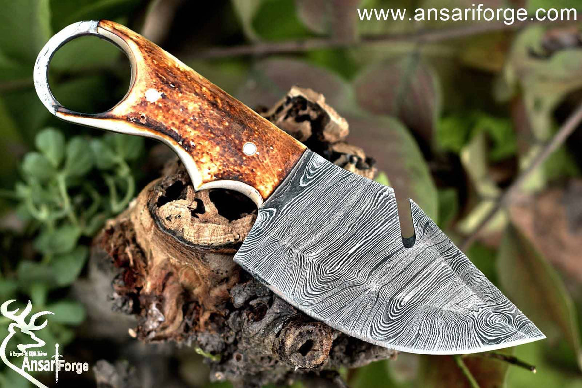 Hand forged Damascus steel gut hook knife with a beautiful twist pattern and burnt bone handle, showcasing its craftsmanship and design.