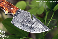 Close-up view of the 3.5-inch drop point blade of the Damascus knife with gut hook, highlighting the intricate Damascus steel layers and sharp edge.