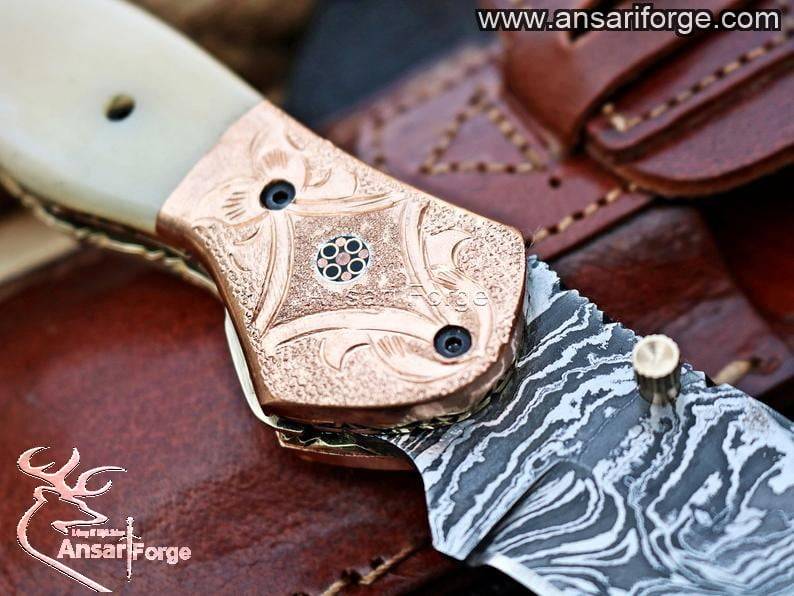 Close-up of twist pattern Damascus folding knife blade with brass bolsters.