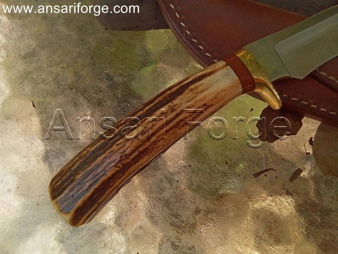 Handmade hunting knife with a drop point blade, brass hilt, stag antler handle, and brown leather sheath.