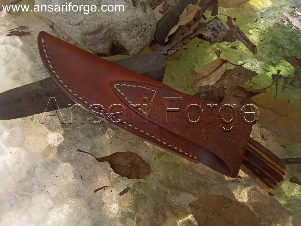 Handcrafted hunting knife with drop point blade, stag antler handle, and leather sheath.