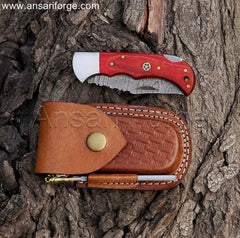 Beautiful Damascus pocket knife featuring a hand-forged twist pattern blade, ergonomic red pakkawood handle, and genuine cowhide leather sheath.