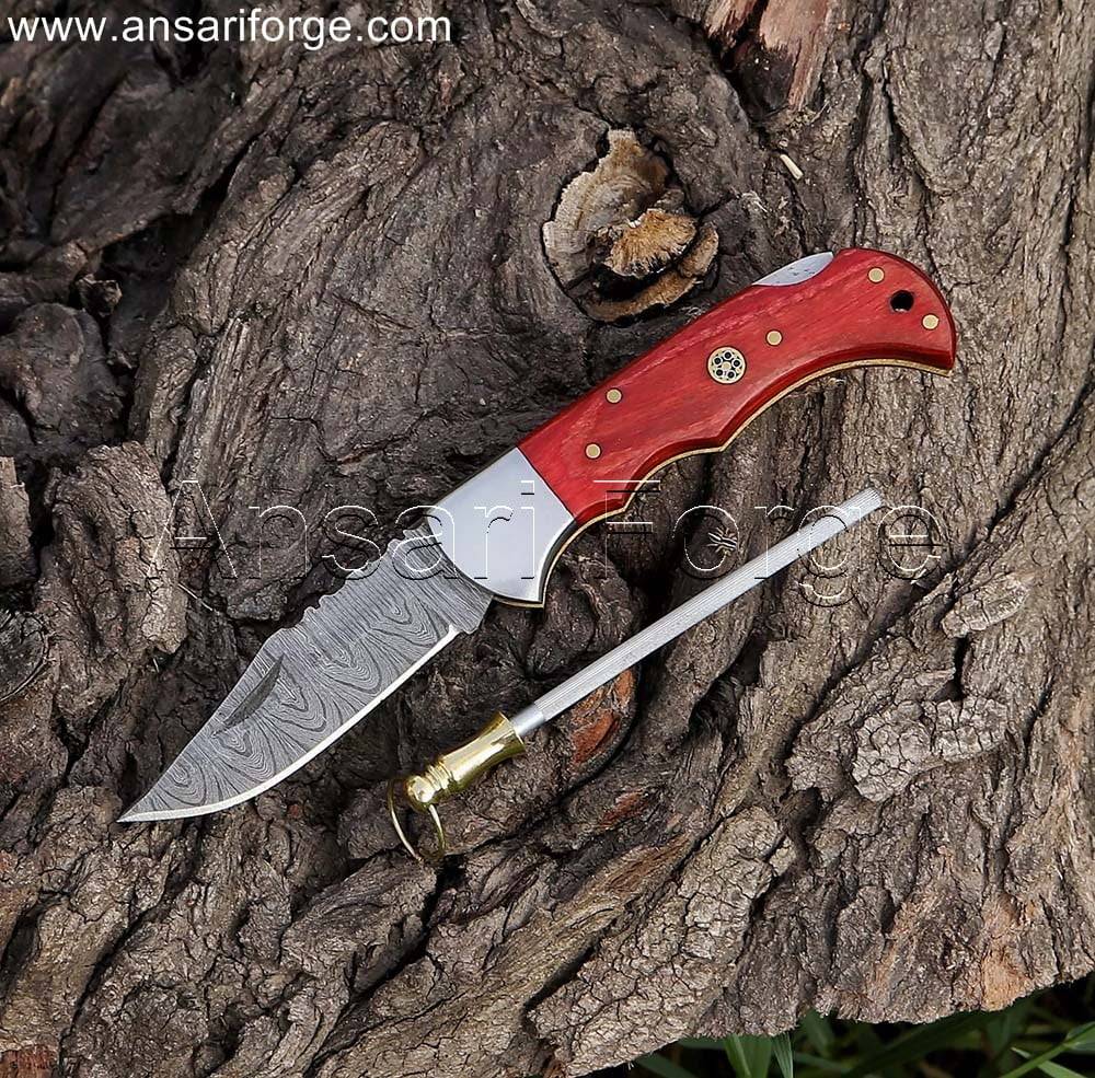 Damascus pocket knife with twist pattern blade, red pakkawood handle, and leather sheath.