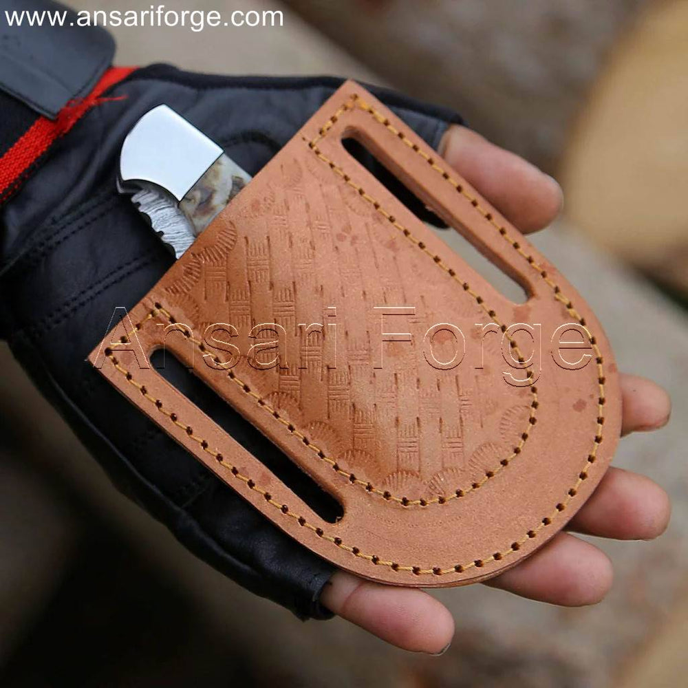Compact Damascus folding knife in a real cowhide leather sheath, ideal for pocket carry.