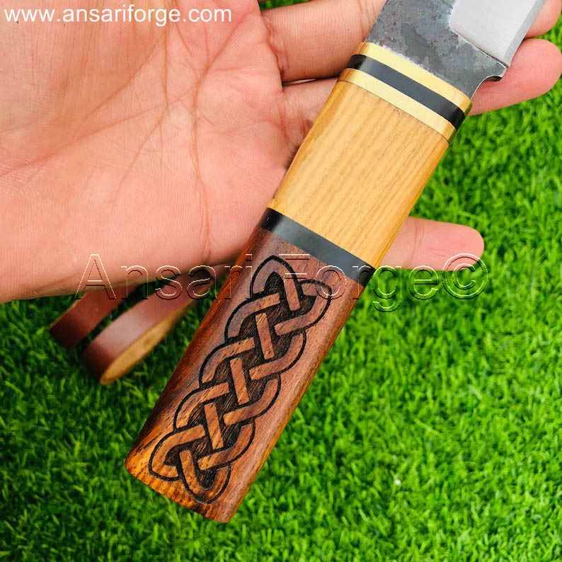 A close-up of the Beagnoth seax knife's handle, showcasing the intricate Norse carvings and the brass bolsters.