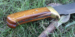 Brass finger guard and rosewood handle of a Damascus steel Bowie knife, emphasizing the combination of style and functionality.
