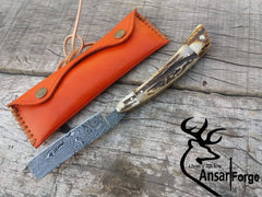 Hand-forged Damascus steel straight razor with antler handle.