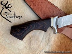 Hand forged Damascus knife with patterned steel blade, dark wood handle, and leather sheath - Ansari Forge custom outdoor tool for hunting and survival.
