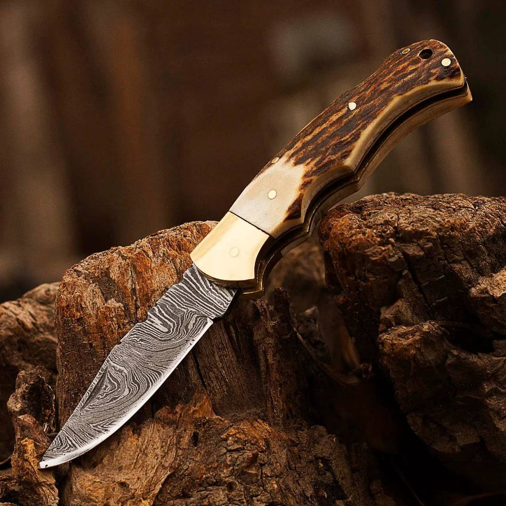 Close-up of the Ansari Forge Damascus folding knife's 2.5-inch drop point blade with a twist pattern.